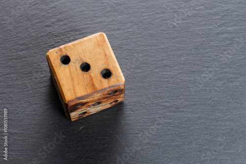 Wooden Dice with Three Dots on Black Slate