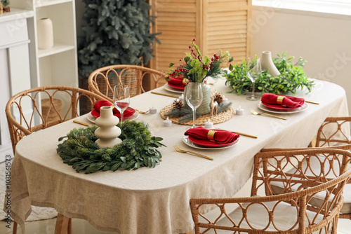 Beautiful festive table setting for Christmas celebration with wreaths in dining room photo