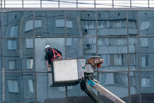 A man on a lift washes mirrored windows of a multi-story building.