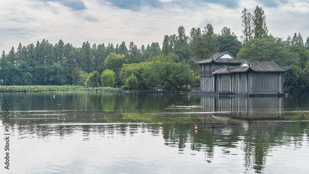 A Chinese-style building by a calm lake. The edges of the roof are curved. Reflection on the water. Lush green vegetation. Lotuses by the shore. Blue sky, clouds. China. Hangzhou
West Lake Xi Hu A Chinese-style building by a calm lake. The edges of the roof are curved. Reflection on the water. Lush green vegetation. Lotuses by the shore. Blue sky, clouds. China. Hangzhou
West Lake Xi Hu