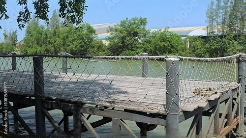A wooden dock with a rope fence extends into a calm river.