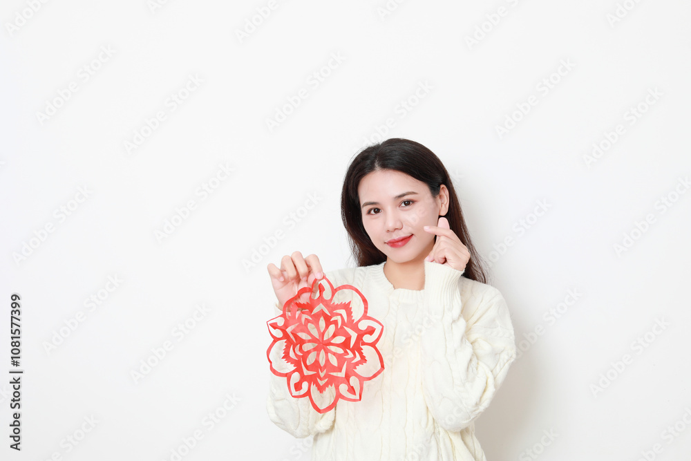 A Chinese woman putting up window decorations at home on the theme of Spring Festival A Chinese woman putting up window decorations at home on the theme of Spring Festival
