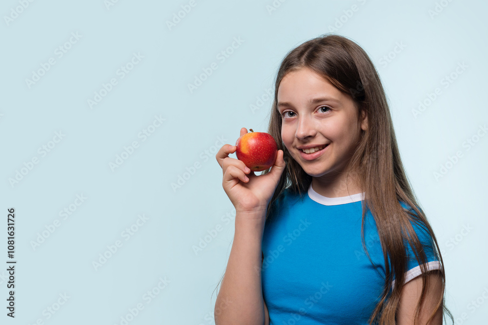 Girl smiling and holding red apple, promoting healthy eating. Girl smiling and holding red apple, promoting healthy eating.