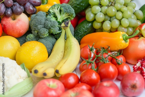 A colorful assortment of fresh fruits and vegetables, including bananas, tomatoes, grapes, apples, and bell peppers, highlighting healthy produce.