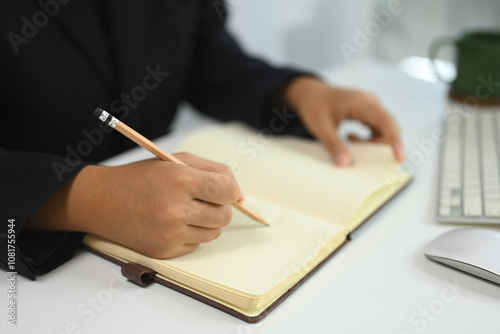 Unrecognizable businesswoman writing in a journal to remember a task at desk