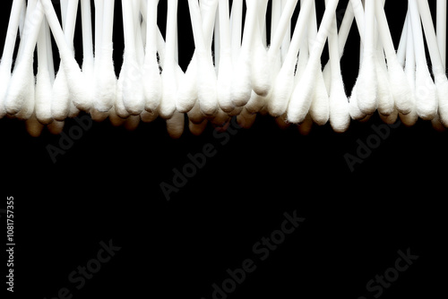 White cotton buds are stacked together on a black background.