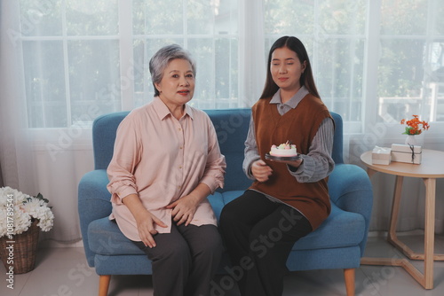 Obraz na płótnie Asian daughter holds birthday cake and delivers it to her mother, making them both happy together. w salonie