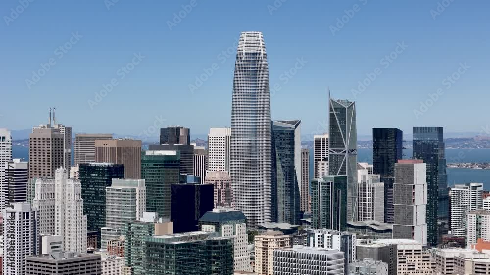 Aerial view of downtown San Francisco's skyline with high-rise buildings and iconic architecture, including the Salesforce Tower. The Bay Bridge is visible in the background Aerial view of downtown San Francisco's skyline with high-rise buildings and iconic architecture, including the Salesforce Tower. The Bay Bridge is visible in the background