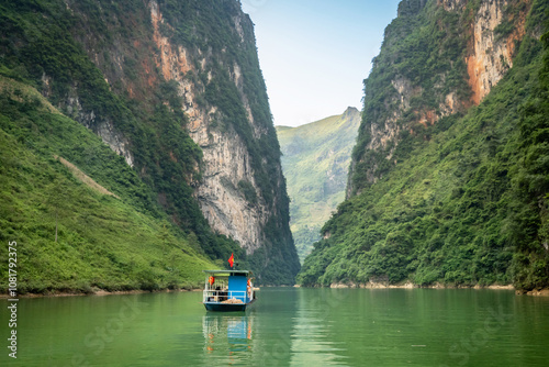 Boat taking tourists on a scenic trip along the Nho Que River in Ha Giang Province, northern Vietnam. The river winds through the towering limestone cliffs of the Dong Van Karst Plateau Geopark. photo