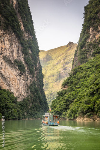 Boat taking tourists on a scenic trip along the Nho Que River in Ha Giang Province, northern Vietnam. The river winds through the towering limestone cliffs of the Dong Van Karst Plateau Geopark. photo