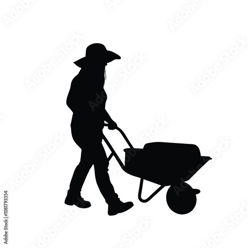 A woman is walking with a wheelbarrow. She is wearing a hat and a shirt. The wheelbarrow is full of dirt