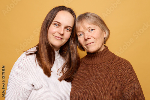 A warm and loving moment between a young woman and her mother against a bright yellow background, showcasing their bond and connection in a cozy atmosphere