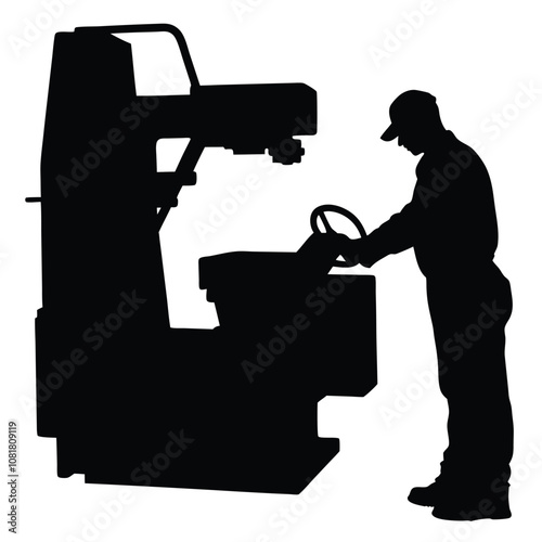 A man is working on a machine. The machine is black and has a large wheel. The man is wearing a hat