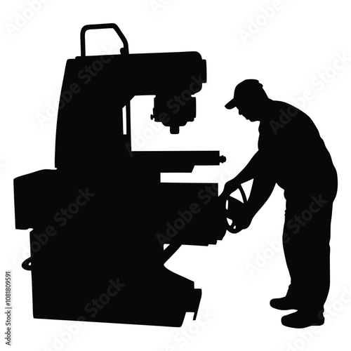 A man is working on a machine. The machine is black and has a large wheel. The man is wearing a hat