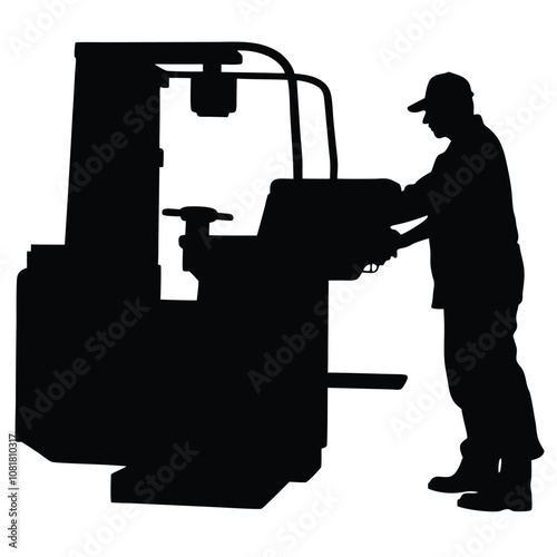 A man is working on a machine. The machine is black and has a large wheel. The man is wearing a hat