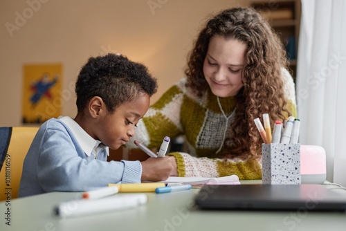 Quadro su tela Side view of adopted Black boy engaged in hand drawing with smiling supportive m