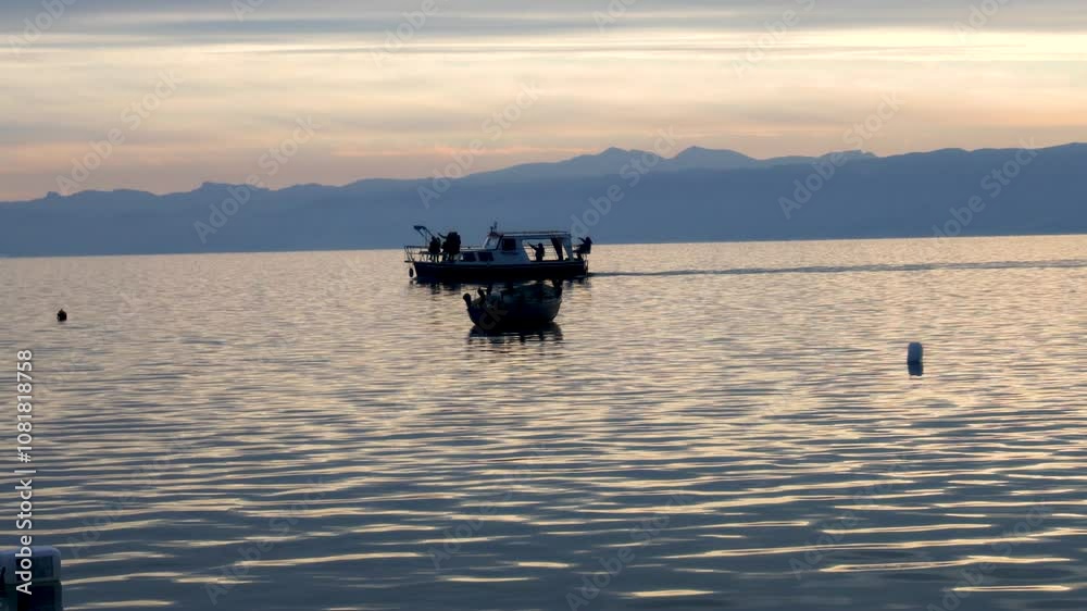 Boats floating peacefully on Ohrid Lake as the sun sets, creating a golden reflection on the water. Norh Macedonia. Boats floating peacefully on Ohrid Lake as the sun sets, creating a golden reflection on the water. Norh Macedonia.