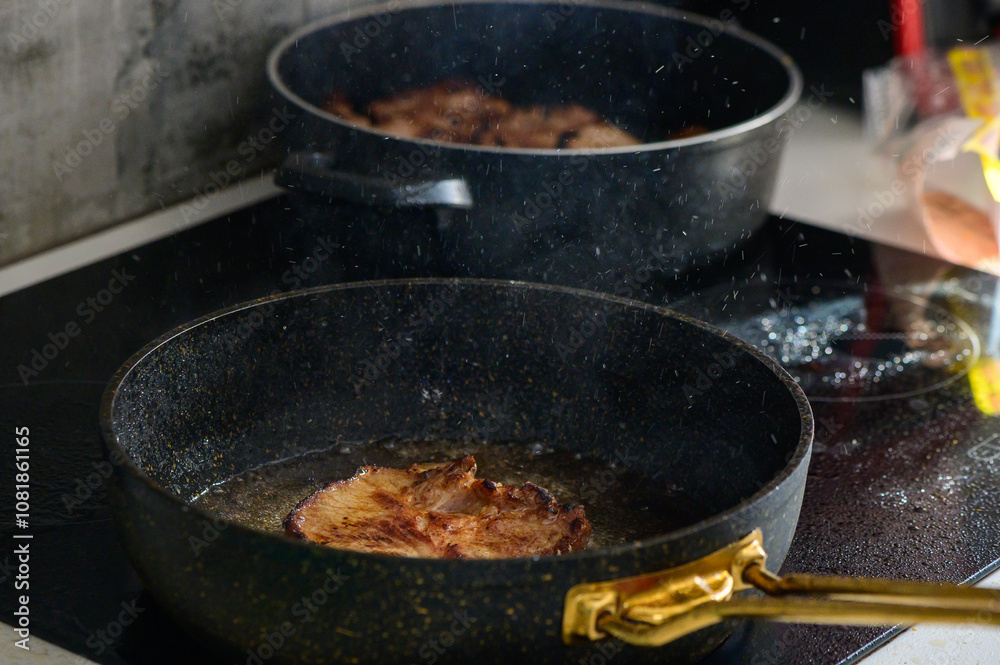 Sizzling pork chops frying in golden oil on a modern stovetop in a cozy kitchen setting at home Sizzling pork chops frying in golden oil on a modern stovetop in a cozy kitchen setting at home