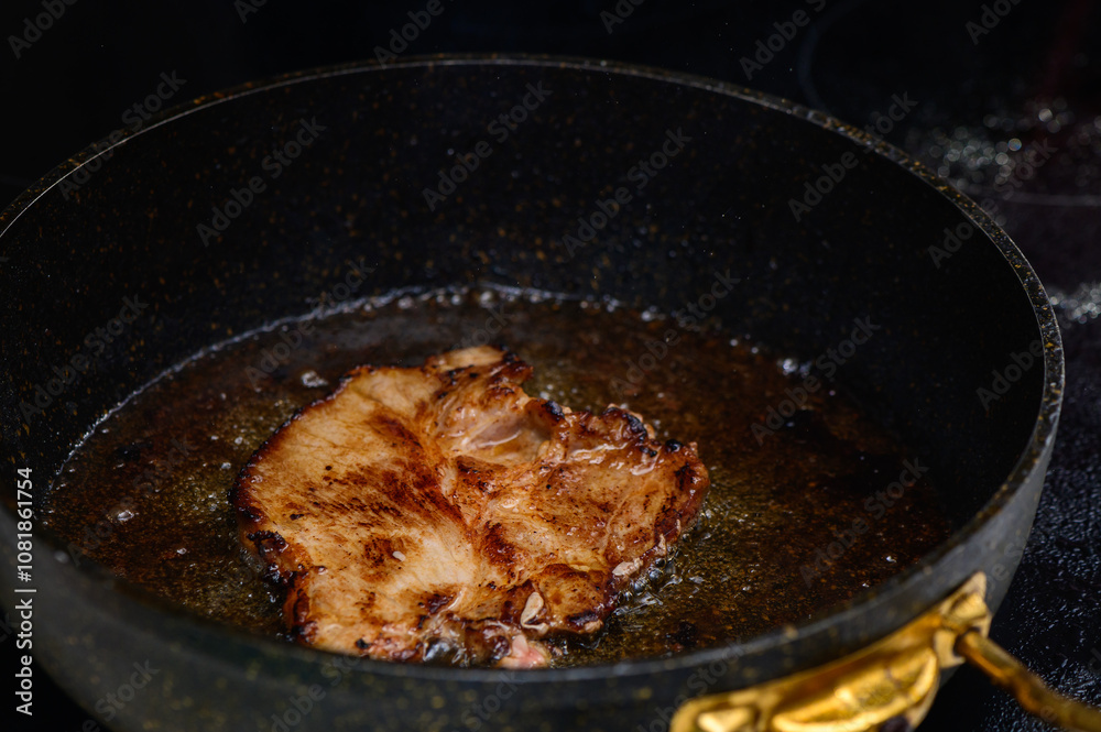 Sizzling pork chop frying in a cast iron skillet with golden edges in a cozy kitchen setting Sizzling pork chop frying in a cast iron skillet with golden edges in a cozy kitchen setting