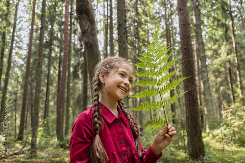 Little girl walking in forest on sunne day admiring nature photo