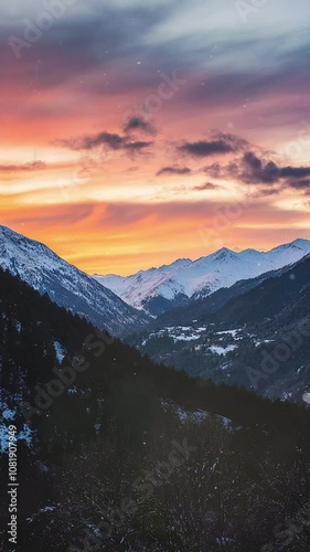 Majestic Snowy Mountain Landscape at Vibrant Sunset. Background. Seamless looping motion design. Video animation. A breathtaking view of snow-covered mountains under a stunning sunset sky. The