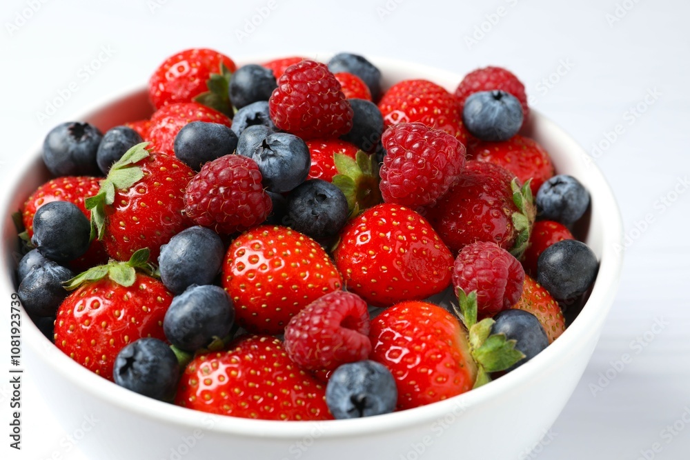 Different fresh ripe berries in bowl on the table, top view Different fresh ripe berries in bowl on the table, top view