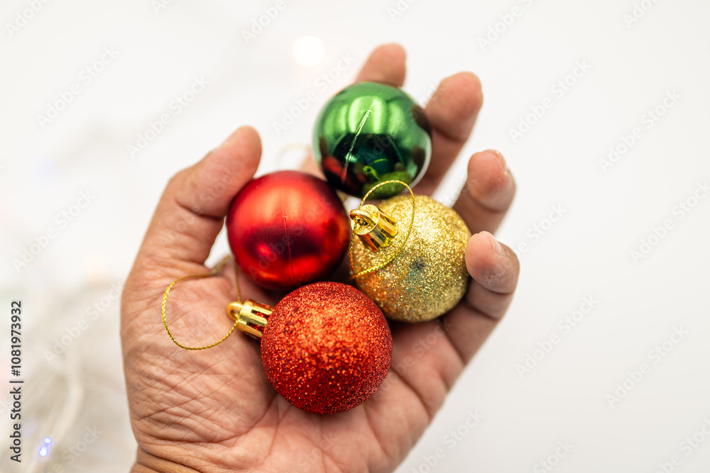 Feel the warmth of the holiday season with this close-up image of a hand gently holding colorful Christmas ornaments. Feel the warmth of the holiday season with this close-up image of a hand gently holding colorful Christmas ornaments.