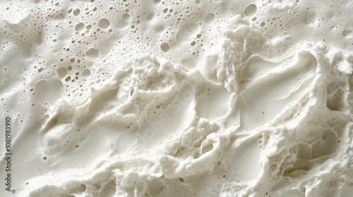 A close-up view of thick creamy foam shows dynamic patterns and bubbles, suggesting a freshly whipped dairy product or a culinary preparation