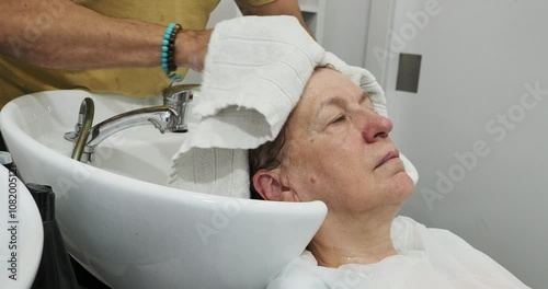 Hairdresser rinses a female client hair in a salon, showcasing professional haircare and attention to detail photo