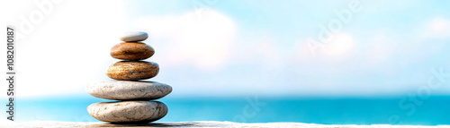 A serene stack of smooth pebbles rests on a ledge, overlooking a calming blue ocean, symbolizing balance and tranquility. photo