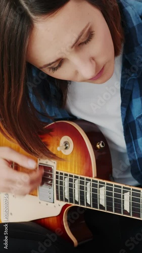 Portrait of female guitarist playing chords on electric guitar. Vertical video