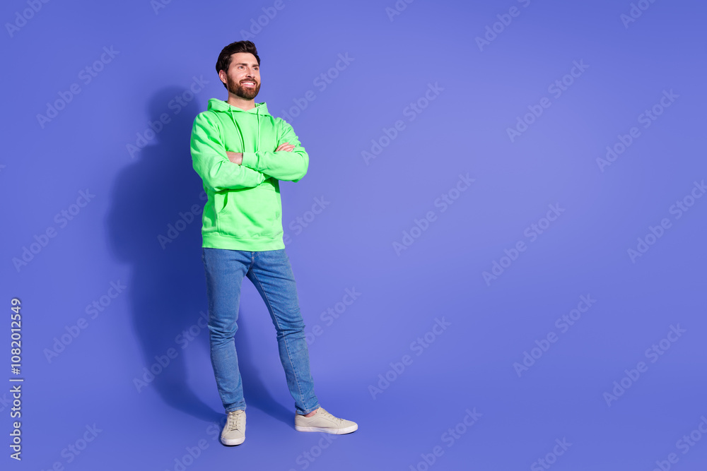 Full size photo of pretty young male look empty space crossed hands confident wear trendy green outfit isolated on purple color background Full size photo of pretty young male look empty space crossed hands confident wear trendy green outfit isolated on purple color background