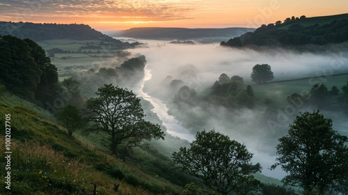 Explore the tranquil beauty of a mist-covered valley at dawn with a meandering river flowing through