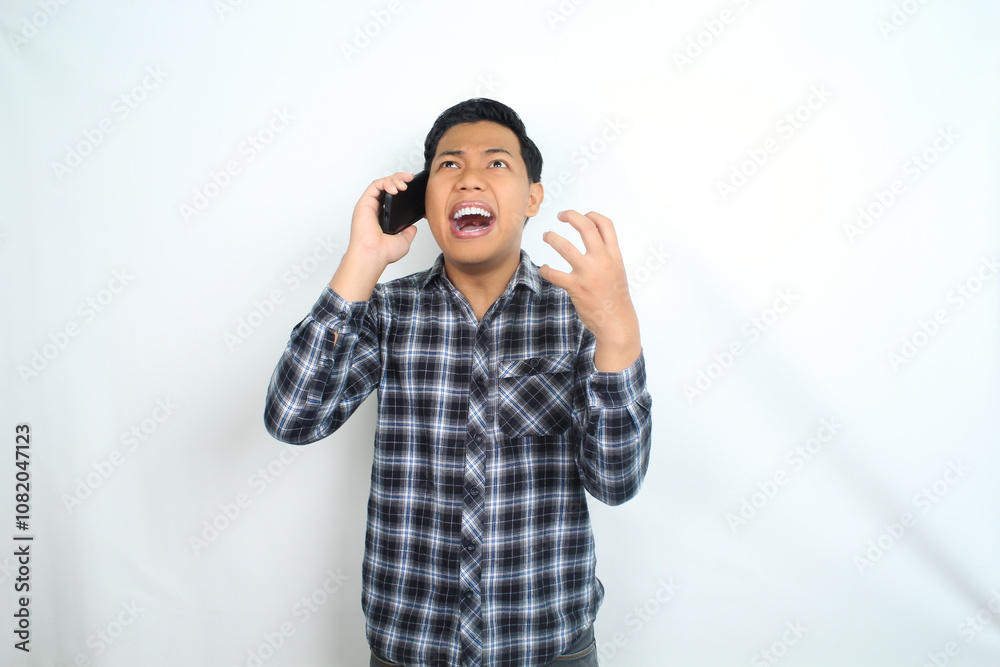 angry asian man raising hand talking on mobile phone with furious face wear casual shirt isolated on white