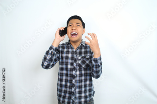 angry asian man raising hand talking on mobile phone with furious face wear casual shirt isolated on white