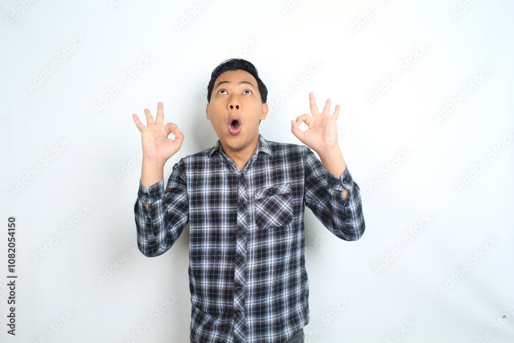 funny asian man showing okay symbol using hand with surprised and shocked expression isolated on white funny asian man showing okay symbol using hand with surprised and shocked expression isolated on white