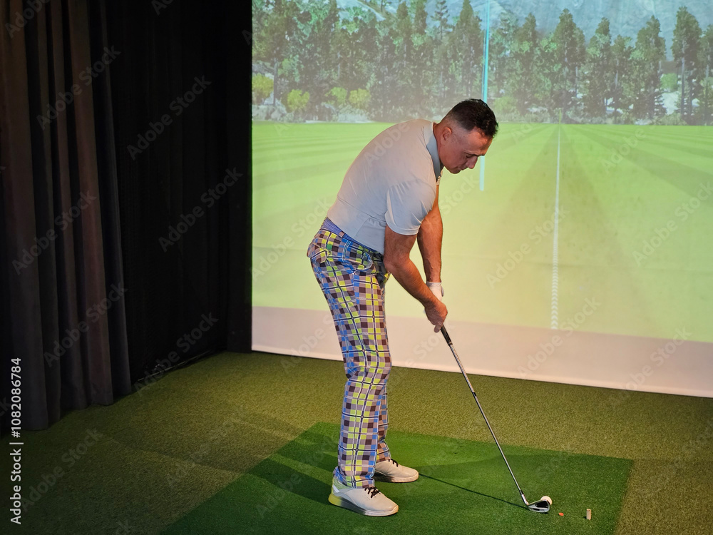 Golf enthusiast practicing his swing indoors with a virtual simulation Golf enthusiast practicing his swing indoors with a virtual simulation