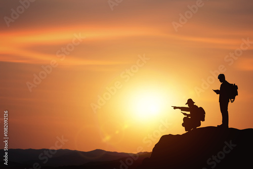 Planning and direction setting ideas. business concept with silhouettes of two businessmen planning trip on mountain with sunset background. photo