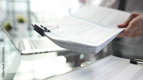 A man is writing on a piece of paper with a pen on a laptop