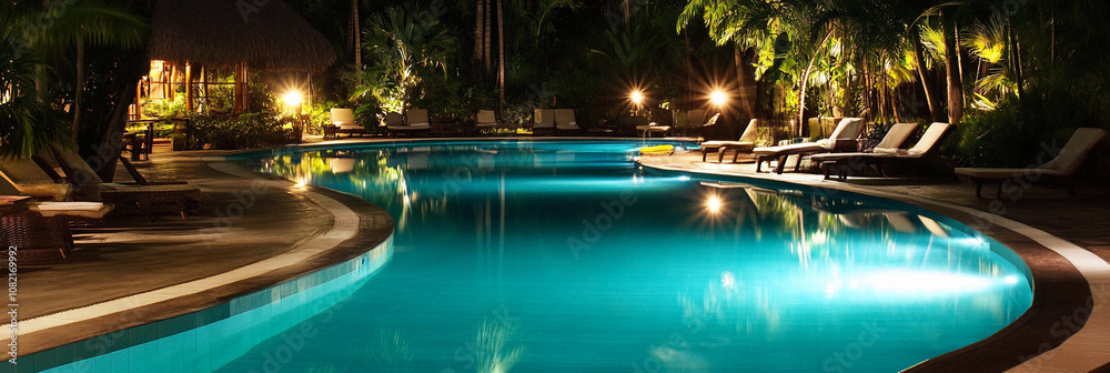Relaxing evening by the illuminated pool surrounded by lush greenery