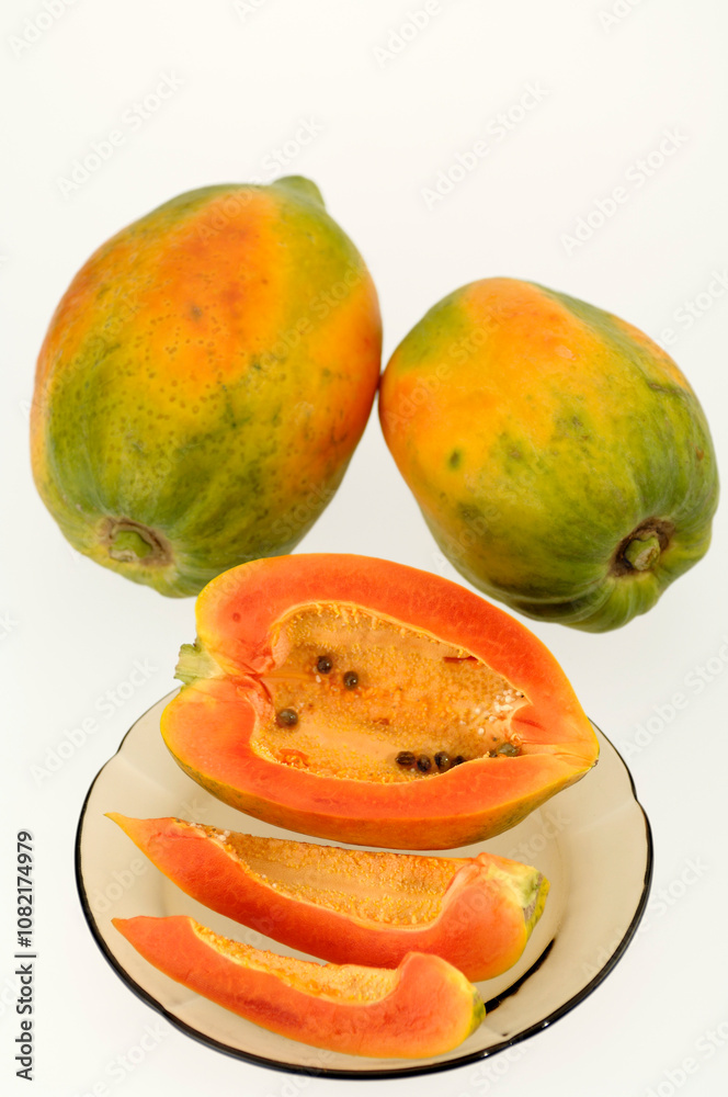 two full Papaya with three small pieces in plate on white background two full Papaya with three small pieces in plate on white background