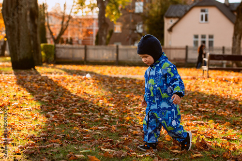 A joyful little boy in his winter coat and hat plays happily in the park, surrounded by the love and warmth of his smiling parents photo