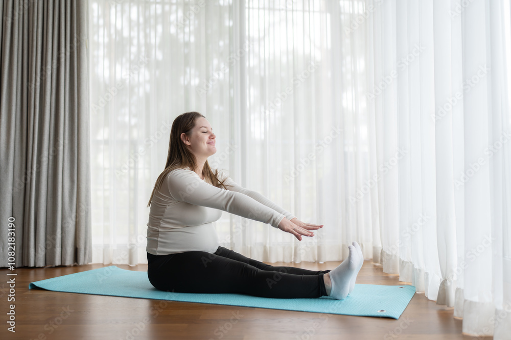 Gen Z pregnant woman practicing yoga at home. Stretching exercise. Expectant mother doing prenatal training class. Gen Z pregnant woman practicing yoga at home. Stretching exercise. Expectant mother doing prenatal training class.