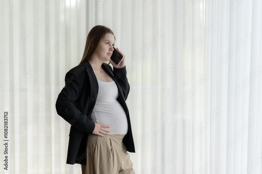 White pregnant woman talking on the phone. Pregnant businesswoman talking on the phone while working. White pregnant woman talking on the phone. Pregnant businesswoman talking on the phone while working.