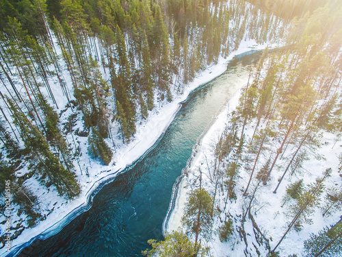 Aerial drone view of cold blue river and snow winter forest in Finland, Lapland photo