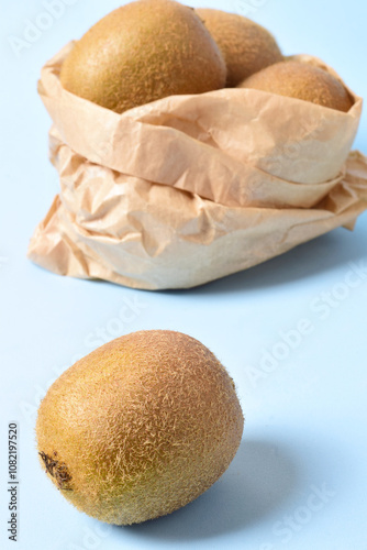 Vertical shot, kiwis in kraft paper bag and blue background.