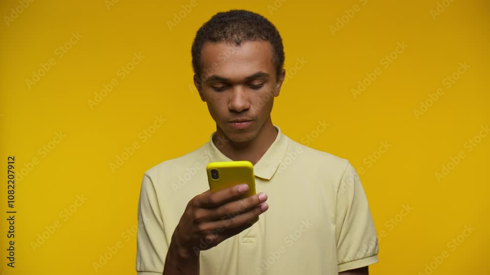 Pensive Man Holding Smartphone Against Yellow Background Pensive Man Holding Smartphone Against Yellow Background
