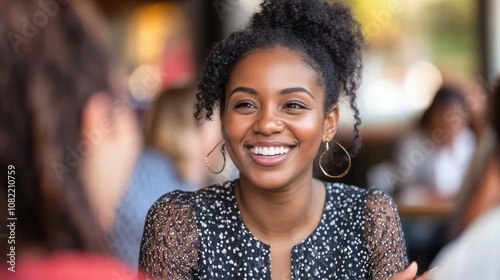 Joyful Young Woman Smiling Brightly While Engaging in Conversation with Friends in a Lively Cafe Setting