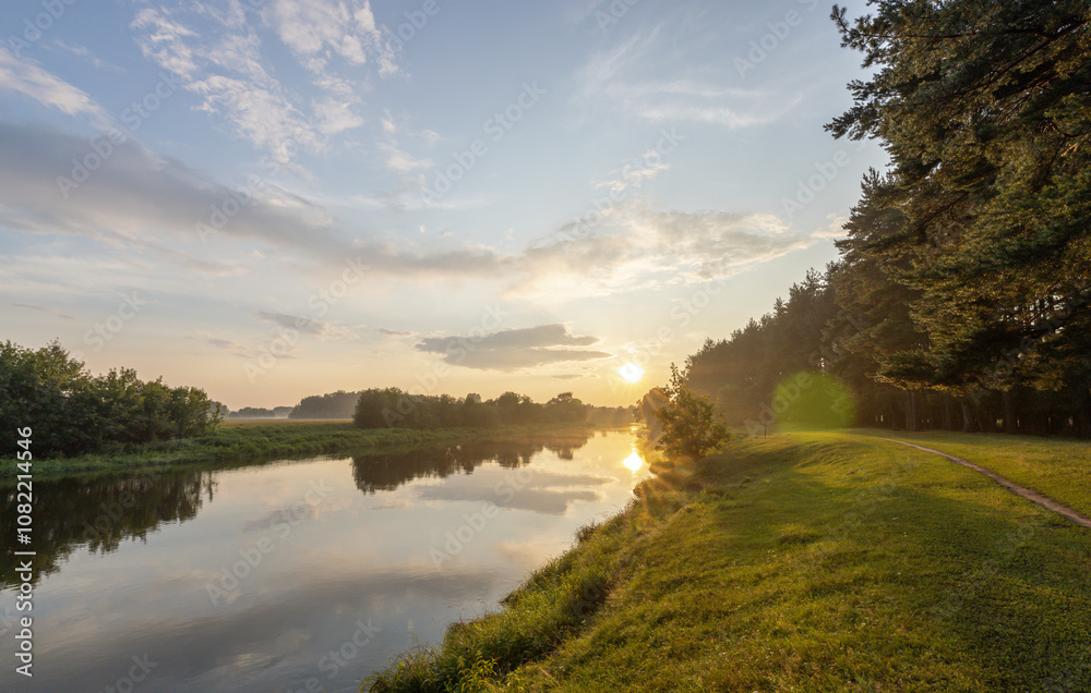 Fototapeta premium Beautiful sunset over a river with trees in the background