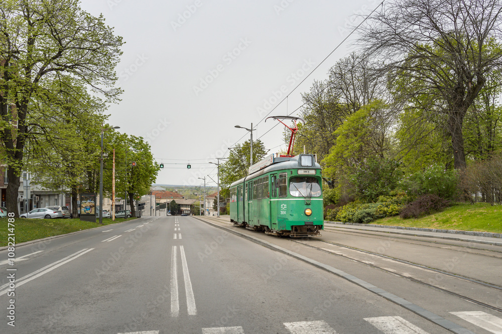 Fototapeta premium Green trolley is traveling down a street